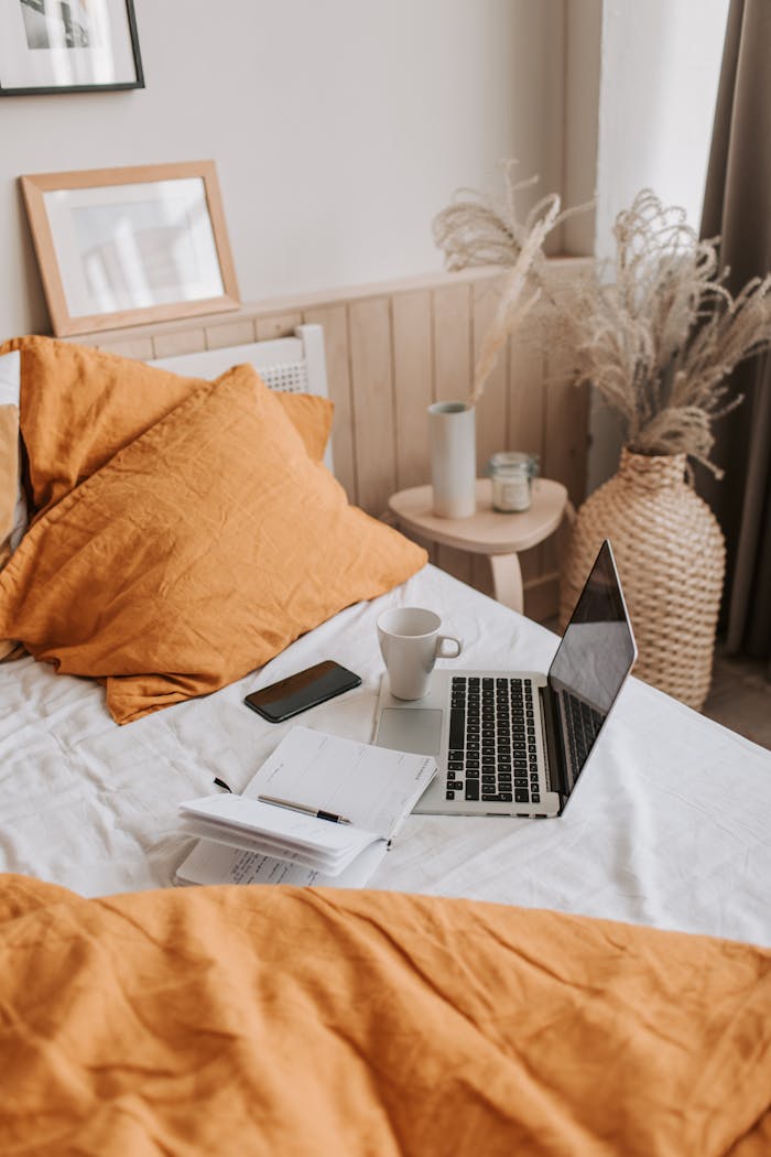 Mastering the First Impression: Your intriguing post title goes here From above of open netbook with black screen and cup of coffee with smartphone and notebook placed on crumpled bed sheet in bedroom with big vase on floor